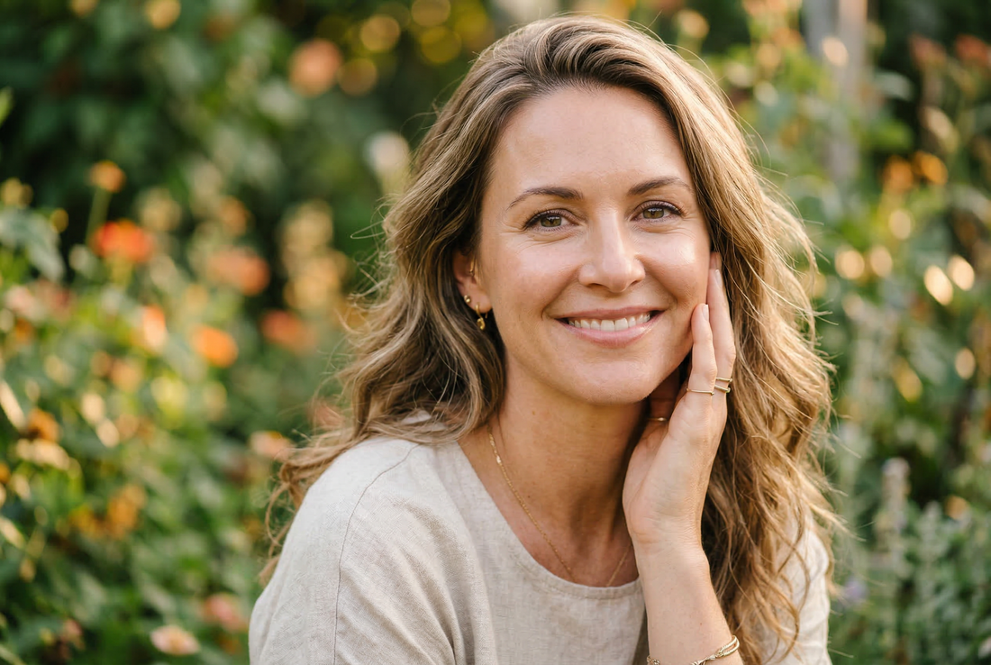 Woman with radiant glowing skin touching her cheek in golden hour light