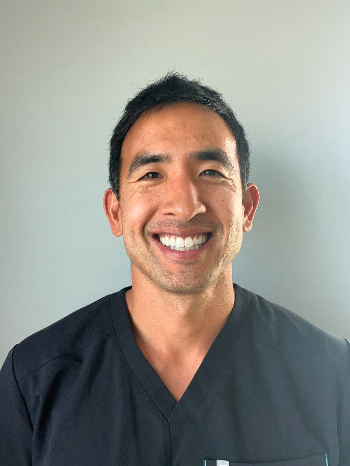Dr John Kim wearing black scrubs against a plain background