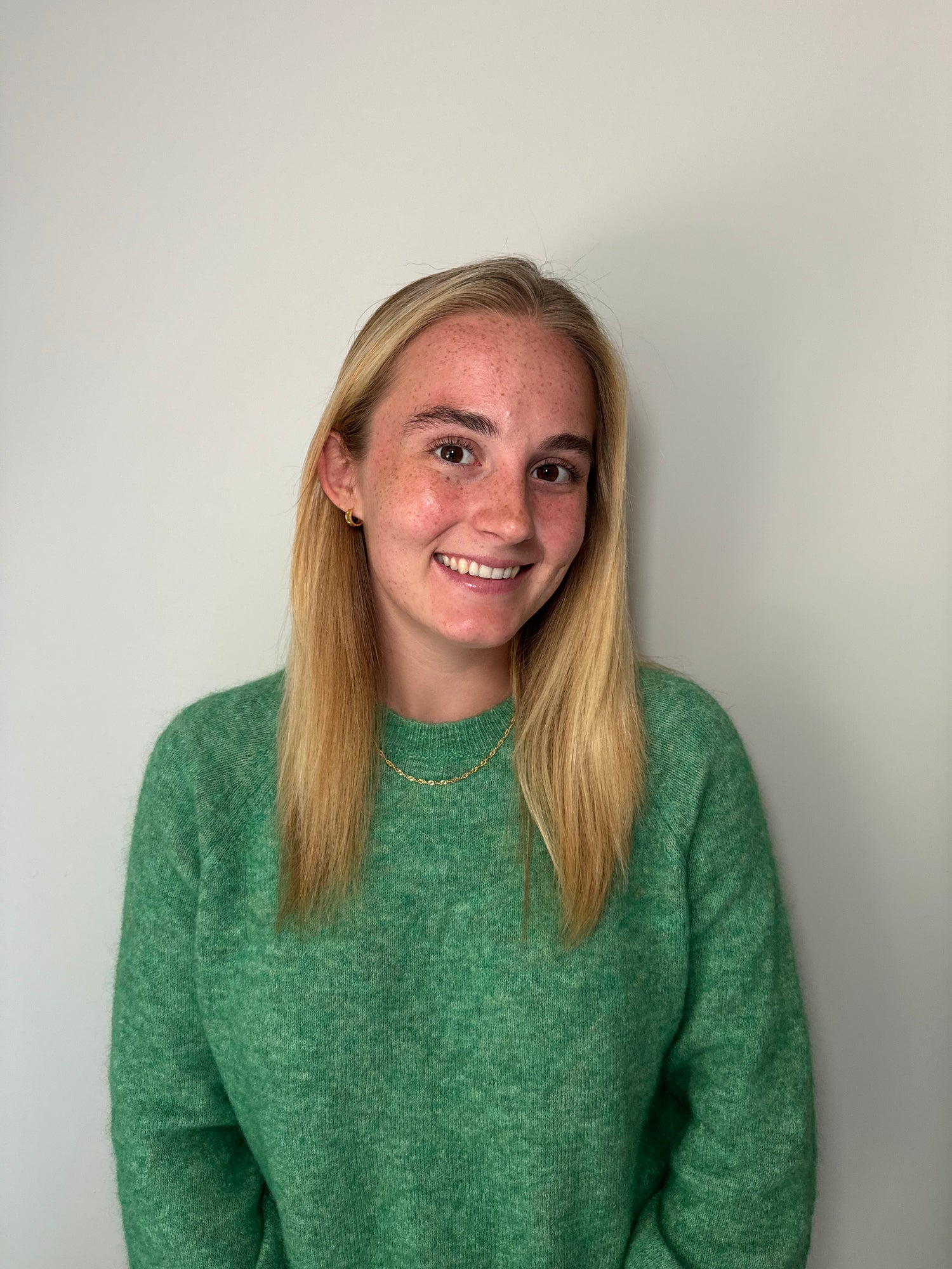 Kathryn wearing a green sweater against a plain background